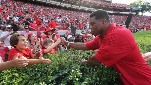 Georgia politicians, including U.S. Senate candidate Herschel Walker, a Republican, rallied behind the state's college football teams over the weekend. Above, Walker greets fans before he is introduced as a member of Georgia's 1980 National Championship team during half time ceremonies against UAB in a NCAA college football game on Sept 11, 2021, in Athens. (Curtis Compton / Curtis.Compton@ajc.com)