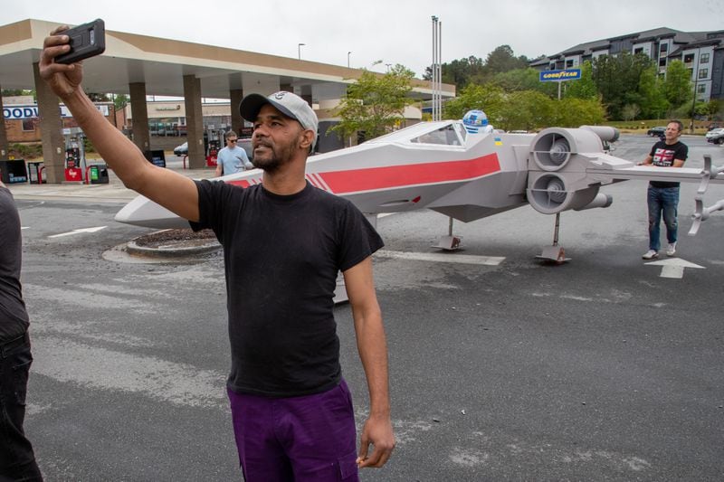 Kevin Nelson takes a selfie in front of a near lifelike replica of an X-Wing Starfighter from Star Wars at Embry Hills shopping Center in Embry Hills Saturday, April 16, 2022. (Steve Schaefer / steve.schaefer@ajc.com)