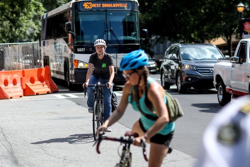 Two cyclists arrive for a rally on July 24, 2019, in Atlanta on West Peachtree Street, near where William Alexander was hit and killed by a bus on July 17th while riding an e-scooter. Rally organizers were demanding that the city prioritize protected bike and scooter lanes. BRANDEN CAMP/SPECIAL