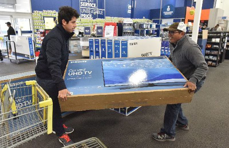 Ramiro Diaz (right) and his son Gabriel Dias load a television onto their cart inside Best Buy in Duluth on Friday, November 25, 2016. HYOSUB SHIN / HSHIN@AJC.COM