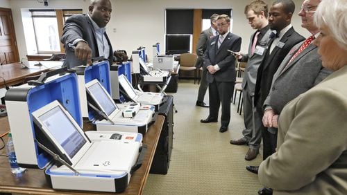 Dwayne Broxton, left, a regional sales director for Hart InterCivic, demonstrates his company’s voting machines to lawmakers on the second day of this year’s General Assembly session. Bob Andres / bandres@ajc.com