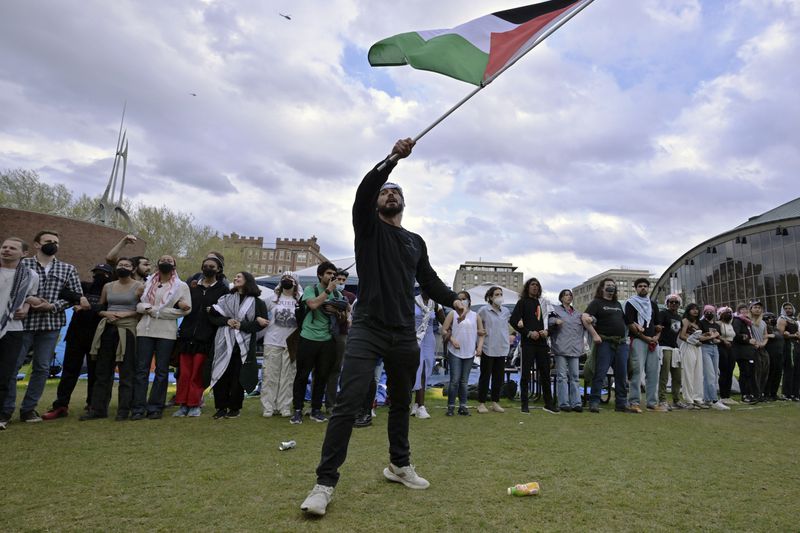 A demonstrator waves a Palestinian flag at a pro-Palestinian encampment at MIT, May 6, 2024, in Cambridge, Mass. Several hundred demonstrators crossed breached barricades to join pro-Palestinian demonstrators that been given a deadline to leave the encampment. (AP Photo/Josh Reynolds)