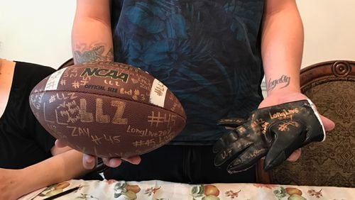 Chris Gonzalez holds a football and glove signed by teammates from Langston Hughes High School in Fairburn for his family. Gonzalez’s brother, Isaiah Gregory, was a defensive end on the football team.
