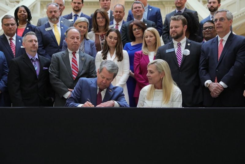 Gov. Brian Kemp signs a new package of human trafficking measures into law as first lady Marty Kemp looks on.