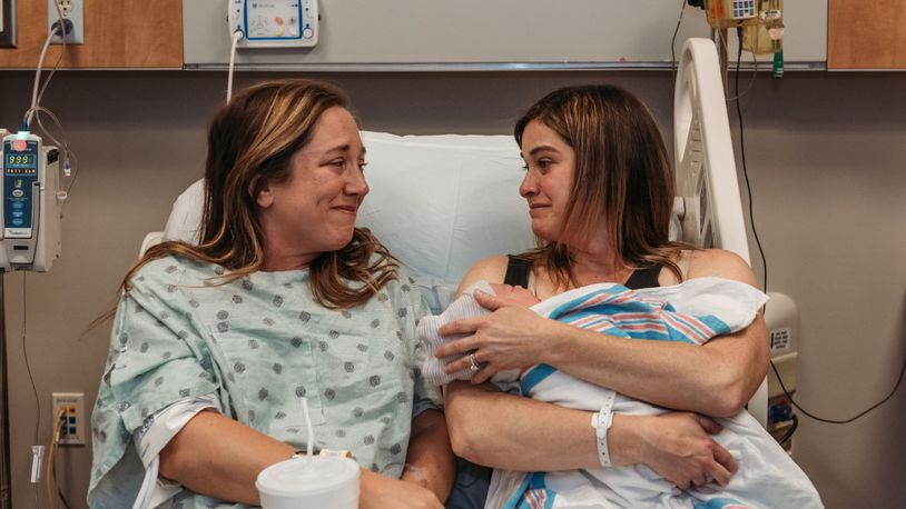 Sisters-in-law Jessica Cooper and Betsy McKamey smile at one another just minutes after Cooper, a gestational carrier, gave birth to McKamey's baby boy. Courtesy of Betsy McKamey