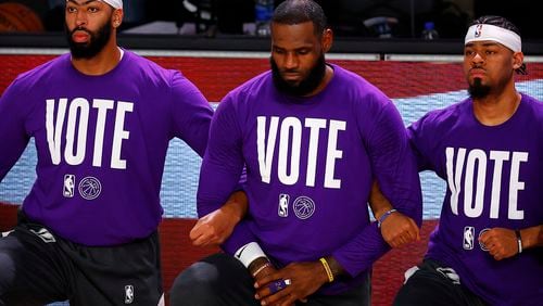 Los Angeles Lakers Anthony Davis, left, LeBron James, center, and Quinn Cook kneel during the national anthem with VOTE shirts on prior to the start of the game in September. James has started a voting rights organization that will try to call attention during the All-Star Game weekend in Atlanta to legislation moving through the Georgia Legislature that would place restrictions on voting. (Mike Ehrmann/Getty Images/TNS)