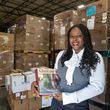 Niclette Mundabi poses with some of the French books she helping to send to the Democratic Republic of Congo in March in front of stacks of shipments at the Books for Africa warehouse in Marietta. PHIL SKINNER FOR THE ATLANTA JOURNAL-CONSTITUTION