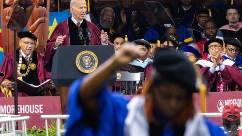 President Joe Biden speaks at the commencement ceremony at Morehouse College as Assistant Professor Taura Taylor raises her fist in protest of the Gaza war in Atlanta on Sunday, May 19, 2024. (Arvin Temkar / AJC)