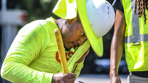Fernando Rosales with RJH electrical contractors worked on installing an electrical box on Northside Drive near I-75 as he wiped away the sweat from the oppressive heat in metro Atlanta on Monday, Aug. 14, 2023. (John Spink / John.Spink@ajc.com)