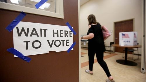 A sign, “Wait here to vote,” is shown as a voter walks toward voting booths during the Georgia runoff election at the North Fulton Government Service Center Tuesday, July 24, 2018, in Sandy Springs, Ga. There have been an increase in election challenges in Fulton County in 2019. (JASON GETZ/SPECIAL TO THE AJC) AJC FILE PHOTO