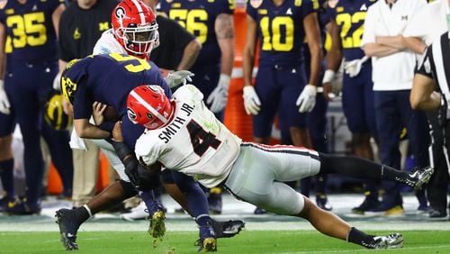 Georgia Bulldogs linebacker Nolan Smith (4) tackles Michigan Wolverines quarterback J.J. McCarthy (9) with Georgia Bulldogs defensive back Lewis Cine (16) for no gain in the 2nd quarter of the 2021 College Football Playoff semifinal between the Georgia Bulldogs and the Michigan Wolverines at the Orange Bowl at Hard Rock Stadium in Miami Gardens. Curtis Compton / Curtis.Compton@ajc.com