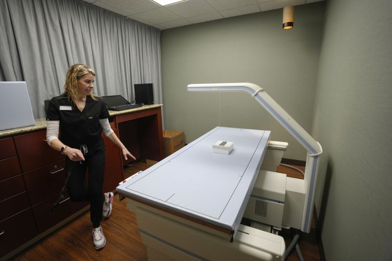 Life Time registered nurse and injections specialist Kylie Simko is pictured with the DEXA (Dual-Energy X-ray Absorptiometry) scan at the MIORA clinic at the Life Time at Target Center, Wednesday, April 3, 2024, in Minneapolis. Luxury athletic club operator Life Time launched a program that offers comprehensive medical testing, personalized training and a host of alternative therapies like cryotherapy. The Miora program also offers Ozempic and other weight loss drugs through the clinic that opened in Minneapolis last year. (AP Photo/Abbie Parr)