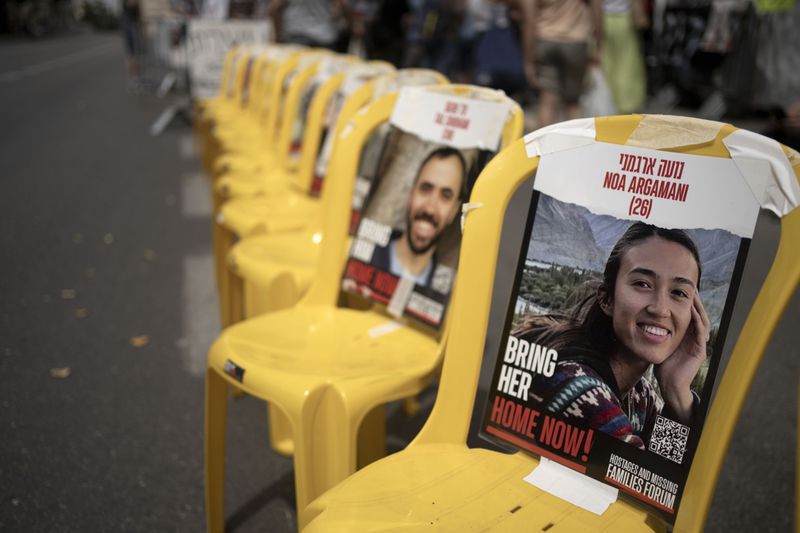 A poster of Noa Argamani is taped to one of the empty chairs for hostages held by Hamas in the Gaza Strip as relatives and their supporters gather together to mark the start of Shabbat, outside of Israeli Prime Minister Benjamin Netanyahu's official residence to call for an immediate deal to release their loved ones, in Jerusalem, Friday, May 10, 2024. (AP Photo/Maya Alleruzzo)