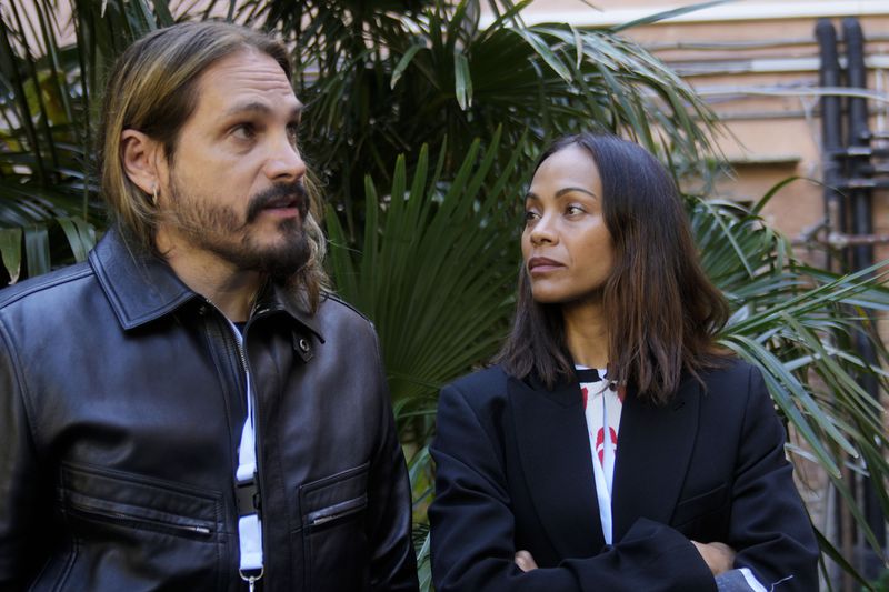 U.S. actress Zoe Saldana looks to her husband and movie director Marco Perego during press preview inside the women's prison at the Giudecca island during the 60th Biennale of Arts exhibition in Venice, Italy, Wednesday, April 17, 2024. A pair of nude feet dirty, wounded and vulnerable are painted on the façade of the Venice women's prison chapel, the work of Italian artist Maurizio Cattelan and part of the Vatican's pavilion at the Venice Biennale in an innovative collaboration between inmates and artists. (AP Photo/Luca Bruno)
