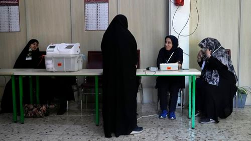 Staff members of a polling station attend to their stations during the parliamentary runoff elections in Tehran, Iran, Friday, May 10, 2024. Iranians voted Friday in a runoff election for the remaining seats in the country's parliament after hard-line politicians dominated March balloting. (AP Photo/Vahid Salemi)