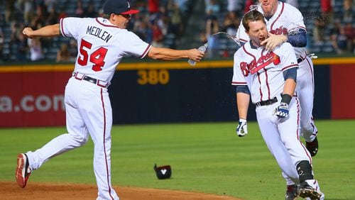 Braves Kris Medlen and Freddie Freeman mug Chris Johnson after he hits a walk-off RBI single to beat the Cleveland Indians 3-2 during the 9th inning at Turner Field on Aug. 28, 2013