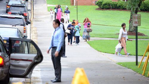 Students and parents arrive on the first day of classes at Woodridge Elementary School in Stone Mountain, Monday. KENT D. JOHNSON/kdjohnson@ajc.com