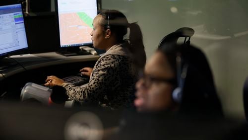 Trainee Beunica Fletched (far left) takes a 911 call April 2 at the Dekalb County 911 communications center. She works beside a supervisor in case she needs assistance. (Miguel Martinez/miguel.martinezjimenez@ajc.com)