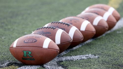 Footballs are placed at midfield before a game at Roswell High School in Roswell.