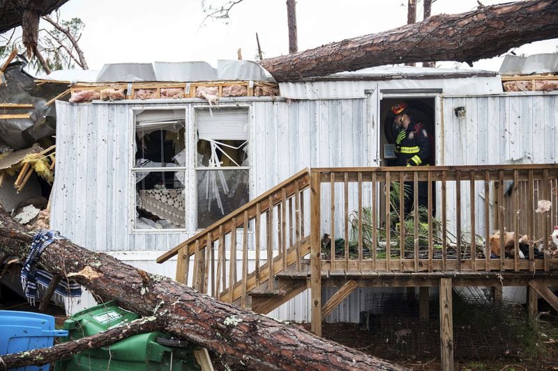 A rescue worker stands in the door of a mobile home Monday, Jan. 23, 2017, in Big Pine Estates that was damaged by a tornado, in Albany, Ga. Fire and rescue crews were searching through the debris Monday, looking for people who might have become trapped when the storm came through. (AP Photo/Branden Camp)