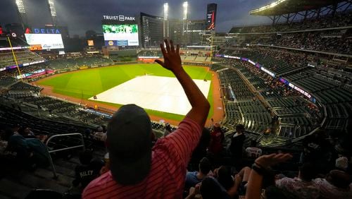 A fan dances in the rain before a rain-delayed baseball game between the Atlanta Braves and the San Diego Padres, Saturday, May 18, 2024, in Atlanta. The game was eventually postponed. (AP Photo/Mike Stewart)