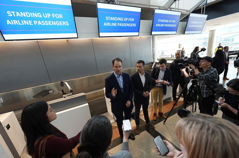 Colorado Attorney General Phil Weiser, back left, responds to questions as U.S. Transportation Secretary Pete Buttigieg looks on after a news conference to announce a new partnership that will streamline how consumer complaints against airlines are resolved in the terminal at Denver International Airport Tuesday, April 16, 2024, in Denver. (AP Photo/David Zalubowski)