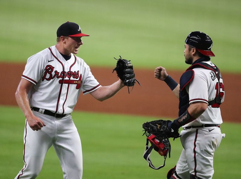 Mark Melancon (left) celebrates closing out the 7-4 win against the Tampa Bay Rays with catcher Travis d’Arnaud in the home opener Wednesday, July 29, 2020, at Truist Park in Atlanta.