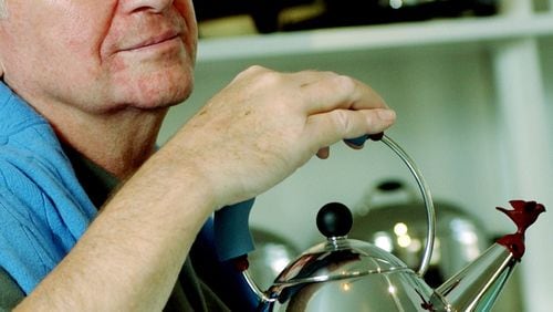FILE- In this Oct. 21, 2003 file photo, architect and designer Michael Graves poses with a teapot he designed at his studio in Princeton, N.J. Graves, who designed modern and whimsical postmodern structures and later household goods sold at Target stores has died. He was 80 years old. (AP Photo/Daniel Hulshizer, file)