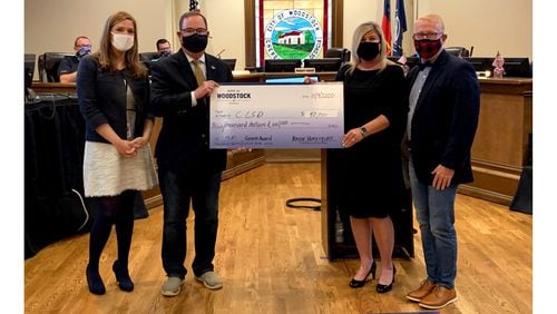 Woodstock Mayor Henriques presents a $90,000 check to Cherokee County schools Superintendent Brian Hightower at the City Council meeting Monday, Nov. 9. The grant will fund mobile WiFi hotspot devices.