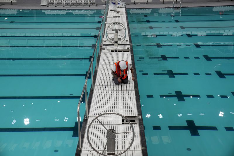 A man works at the Olympic Aquatic Center, Wednesday, March 6, 2024 in Saint-Denis, outside Paris. The aquatic center, whose construction is supervised by the Greater Paris metropolitan authority, will host the artistic swimming, water polo and diving events during the Paris 2024 Olympic Games. (AP Photo/Christophe Ena)