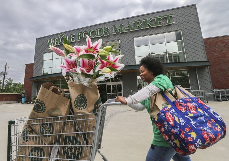 Personal shopper Zyra Money emerges from Whole Foods Market at Buckhead Market Place on June 16, when Amazon announced it will buy the higher-end grocer for $13.7 billion. Whole Foods has 465 stores worldwide and 87,000 employees. JOHN SPINK/JSPINK@AJC.COM.