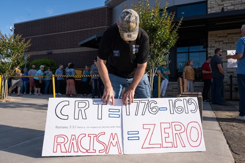 Rick Cox, who has a son in the Cherokee County school system, holds signs outside the school board chambers in Canton before a packed-to-capacity meeting on May 20, 2021. (Credit: Ben Gray for the Atlanta Journal-Constitution)