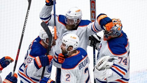 Edmonton Oilers' Mattias Ekholm (14), goalie Stuart Skinner (74), Evan Bouchard (2) and Zach Hyman (18) celebrate after winning against the Vancouver Canucks in Game 7 of an NHL hockey Stanley Cup second-round playoff series, in Vancouver, British Columbia, on Monday, May 20, 2024. (Ethan Cairns/The Canadian Press via AP)