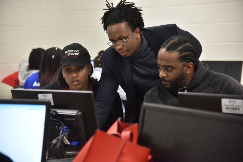 Ibrahiim J. El-Amiir (center), a college adviser and member of the College Advising Corps who is assigned to Booker T. Washington High School, helps Taliyah Rutledge, 18, and her father Warren Rutledge (right) as Taliyah Rutledge fills out application for Federal Student Aid during Achieve Atlanta FAFSA Clinic at Therrell High School in Atlanta on Tuesday, October 23, 2018. HYOSUB SHIN / HSHIN@AJC.COM