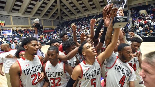 Tri-Cities DeMarcus Johnson (5) helps hoist the Class AAAAAA championship trophy March 9, 2019, at the Macon Centreplex in Macon. Tri-Cities defeated Tuker, 46-43, for the state title.