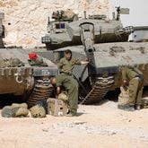 Israeli soldiers make preparations in front of Merkava tanks as they man a position at an undisclosed location on the border with Lebanon on Sunday, Oct. 22, 2023. Lebanon's Iran-backed Hezbollah and allied Palestinian factions have traded cross-border fire with Israel for days, after Hamas gunmen attacked communities in southern Israel on Oct. 7. (Jalaa Marey/AFP/Getty Images/TNS)