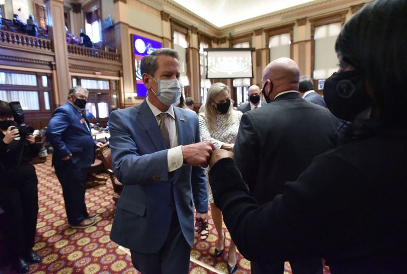 Gov. Brian Kemp exchanges fist bumps with lawmakers Thursday as he leaves the chambers of the Georgia House after delivering the State of the State address. (Hyosub Shin / Hyosub.Shin@ajc.com)