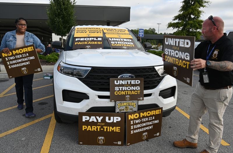 August 4, 2022 Atlanta - Eric Massaro (right) and Aluana Freeman, both members of Teamsters and UPS employees, hold a sign in the employee parking lot after holding a contract rally inside UPS SMART Hub in Atlanta on Thursday, August 4, 2022. The Teamsters were holding a contract rally among workers in preparation for negotiations with UPS coming up over the next year. (Hyosub Shin / Hyosub.Shin@ajc.com)