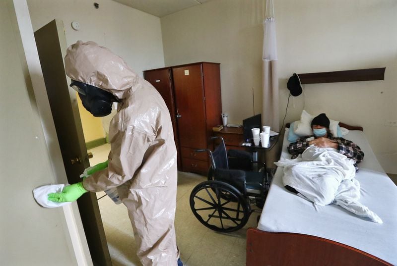 A Georgia Army National Guard infection control member cleans the room of a resident at Legacy Transitional Care in April. Legacy is a for-profit facility where up to four residents live in each room. (Curtis Compton ccompton@ajc.com)