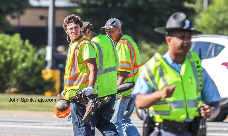 Crews with Wall Asphalt Services collect the boots and hat of their fellow  worker killed Tuesday morning when he was hit by a red pickup truck on Tara Boulevard in Lovejoy. 