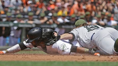 San Francisco Giants’ Eduardo Nunez, left, slides to score on a wild pitch by Atlanta Braves pitcher R.A. Dickey, right, in the first inning Sunday. (AP Photo/Ben Margot)
