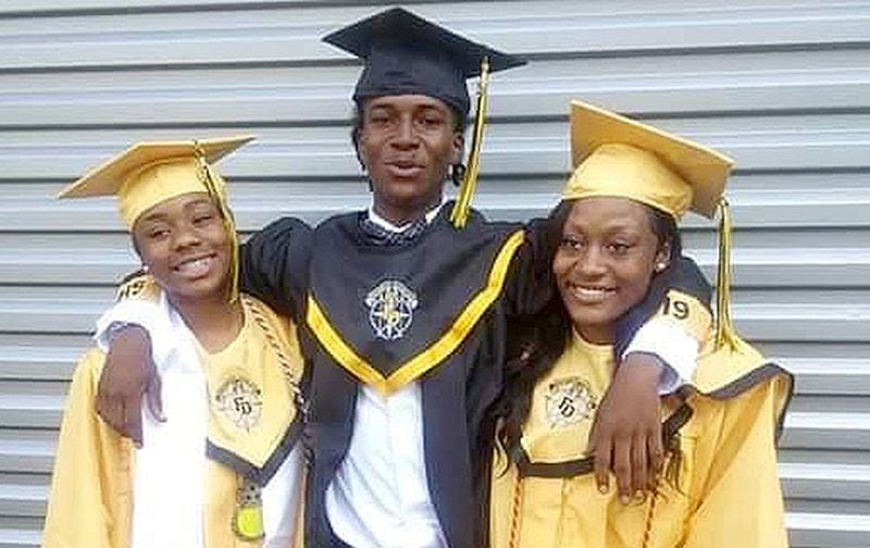 Jalanni Pless, center, stands with his cousin and a friend on the day of his 2019 high school graduation.