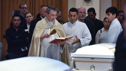 The Rev. John Howren blesses the caskets of Martin Romero, 33, and four of his children -- Axel, 1; Dillan, 4; Dacota, 6; and Isabela Martinez, 10 -- before the funeral Mass at St. Lawrence Catholic Church on July 13, 2017. Romero and his  children were stabbed to death last week in their Loganville home. Nine-year-old daughter Diana Romero survived. HYOSUB SHIN / HSHIN@AJC.COM