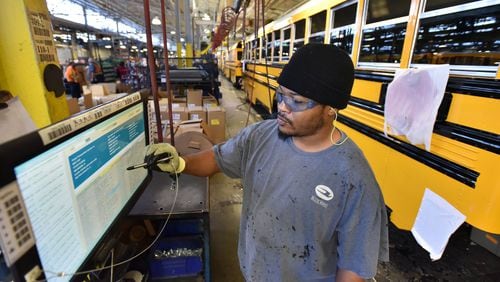 Worker checks his screen naer the Blue Bird assembly line in Fort Valley. The company makes more than 11,000 buses a year and employs 2,400. (Photo: HYOSUB SHIN / HSHIN@AJC.COM)
