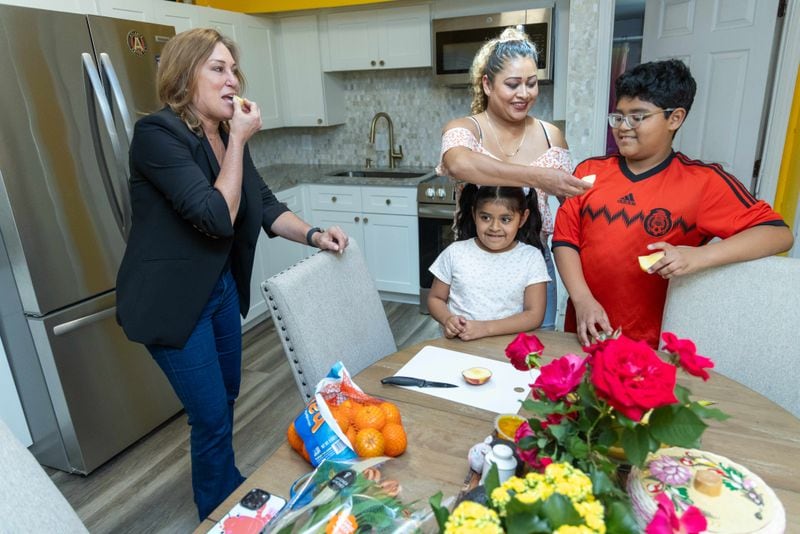 Allison Hill (left) shares an apple with Lucero Liborio and her two children Gabriella Velazquez and Antonio Velazquez in their southwest Atlanta home.   PHIL SKINNER FOR THE ATLANTA JOURNAL-CONSTITUTION