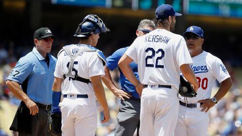 Los Angeles Dodgers manager Dave Roberts, right, talks with starting pitcher Clayton Kershaw, second from right, with trainer Nathan Lucero, as home plate umpire Ben May, left, and Austin Barnes watch during the second inning of a baseball game against the Atlanta Braves in Los Angeles, Sunday, July 23, 2017. Kershaw continued to pitch and completed the second inning, but did not return for the third inning. (AP Photo/Alex Gallardo)