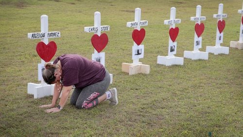 SANTA FE , TX - MAY 21: Parent Lori Simmons prays while visiting a memorial in front of Santa Fe High School on May 21, 2018 in Santa Fe, Texas. A few days earlier, 17-year-old student Dimitrios Pagourtzis entered the school with a shotgun and a pistol and opened fire, killing 10 people.
