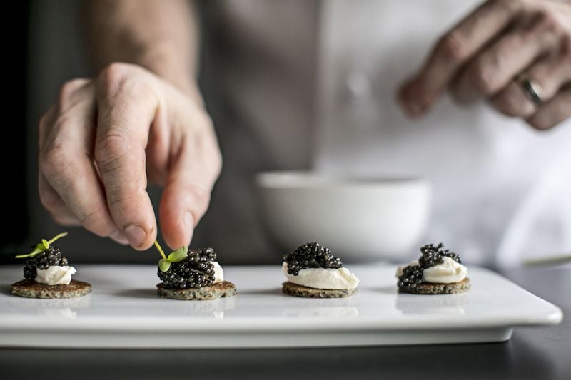 At Saltyard, caviar service features a row of silver dollar cornmeal blinis topped with smoked fromage and a heap of UGA caviar. CONTRIBUTED BY HEIDI GELDHAUSER