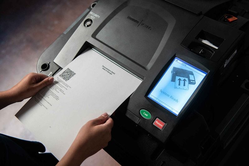 A voter inserts a printed ballot into an optical scanner for tabulation. HANDOUT Georgia Secretary of State’s Office