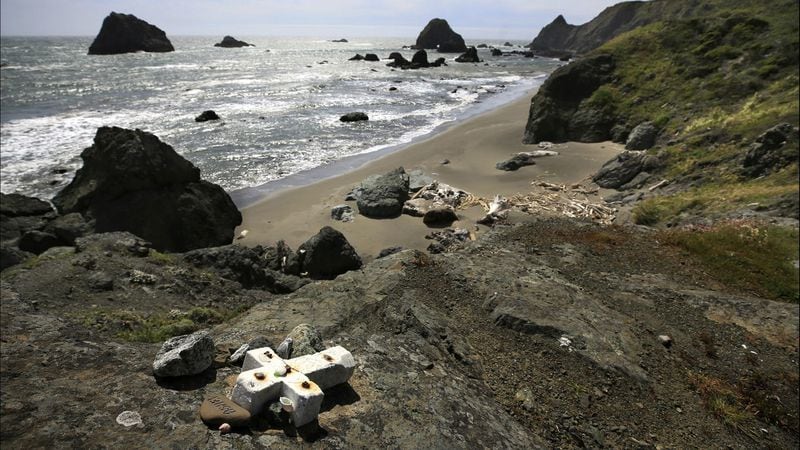 In this May 5, 2017, file photo, a stone memorial cross for Lindsay Cutshall and her fiancé, Jason Allen, is bolted to a cliff above Fish Head Beach near Jenner, Calif., where the couple was found slain in their sleeping bags in 2004.
